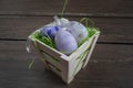 Easter small basket with colored eggs on grey wooden board. Royalty Free Stock Photo