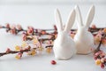 Easter spring decorative composition with white easter ceramic bunny, pink cherry branch. On a white background