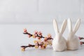 Easter spring decorative composition with white easter ceramic bunny, pink cherry branch. On a white background