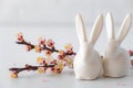 Easter spring decorative composition with white easter ceramic bunny, pink cherry branch. On a white background