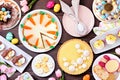 Easter or spring dessert food table scene. Overhead view over a dark wood background.