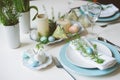 Easter and spring festive table decorated in blue and white tones in natural rustic style, with eggs, bunny, fresh flowers