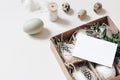 Easter, spring still life. Greeting card, invitation mockup on paper box with quail and hen eggs, feather and green