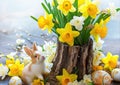 Easter still life with bouquet of daffodils in vase from bark of wood, Easter eggs and cute rabbit