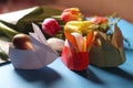 Easter still life. Paper rabbits. Origami. Easter Golden eggs. On the blue table, a bouquet of tulips Royalty Free Stock Photo