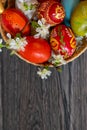 Easter still life with writing space on gry wood and basket with colorful eggs and white flowers