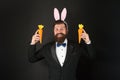 Easter symbol. Holiday celebration. Gentleman with carrot. Easter rabbit black background. Bearded man hold carrots