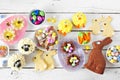 Easter table scene with assorted desserts and sweets over a white wood background