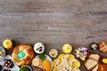 Easter table scene with an assortment of breads, desserts and treats, top view bottom border over a wood background