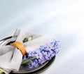 Easter table serving close up. Gray plates, napkin, quail egg, purple jacinth flower on light gray.
