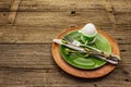 Easter table setting on antique wooden background. Spring holiday card template. Cutlery, crochet napkin, egg, twigs of lilac