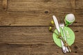 Easter table setting on antique wooden background. Spring holiday card template. Cutlery, crochet napkin, egg, twigs of lilac