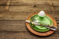 Easter table setting on antique wooden background. Spring holiday card template. Cutlery, crochet napkin, egg, twigs of lilac