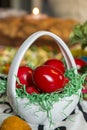 Easter table setting with colored red eggs, bread, green branches decorated, over white plank wooden table with textile Royalty Free Stock Photo