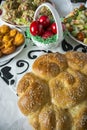 Easter table setting with colored red eggs, bread, green branches decorated, over white plank wooden table with textile Royalty Free Stock Photo