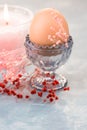 Easter table setting and decoration, egg in crystal cup,spring red and pink small flowers, burning candle Royalty Free Stock Photo