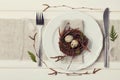 Easter table setting with eggs and spring decoration on rustic background, vintage toning