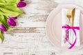 Easter table setting, flatlay ? wedding party, event decoration. Pink dishes and a gold fork and a spoon on a light rustic wooden