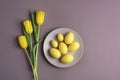 Easter table setting with grey plate, yellow tulip flowers and eggs on background. Top view, flat lay Royalty Free Stock Photo