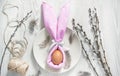 Easter table setting. A napkin in the form of an Easter bunny on a plate. Light background. Copy space