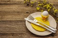 Easter table setting on old wooden background. Spring holiday card template. Cutlery, crochet napkin, egg, flowering sprigs of