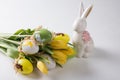 Easter table setting, painted eggs with a bouquet of yellow tulips and an Easter bunny. Royalty Free Stock Photo