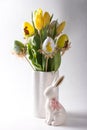 Easter table setting, painted eggs with a bouquet of yellow tulips and an Easter bunny. Royalty Free Stock Photo