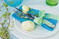 Easter table setting with painted eggs, green spring branch and