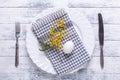 Easter table setting. White egg, napkin on a plate, mimosa flowers, fork, knife on a wooden table Royalty Free Stock Photo