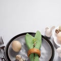 Easter table in trendy natural colors. Gray plates, green napkin, organic eggs, ceramic bunnies.