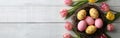 Easter Greetings: Pink Eggs and Yellow Tulips in Bird Nest Basket on White Wooden Table Background - Top View Flat Lay Banner Royalty Free Stock Photo