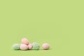 Easter tiny eggs sweets on green background.