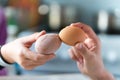 Easter tradition of cracking eggs, two hands hold eggs and try to break each othe egg, close up against blue background