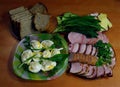 Easter treats. Homemade sausages, pork belly and bacon with greens and eggs under horseradish