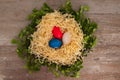 Easter tricolour eggs on a wooden background in the nest Situated on the middle