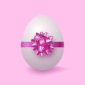 Easter white egg tied with a gift with a purple-pink ribbon with a bow in the form of a flower. Isolated. Royalty Free Stock Photo