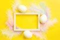 Easter white frame on a bright yellow background of chicken eggs and colored delicate feathers. Spring, religious holiday, Easter Royalty Free Stock Photo