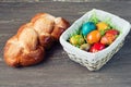 Easter wicker basket with colored eggs and Easter bread on grey wooden board. Royalty Free Stock Photo