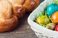 Easter wicker basket with colored eggs and Easter bread on grey wooden board. Royalty Free Stock Photo