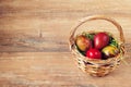 Easter wicker basket with colored eggs on brown wooden board. Royalty Free Stock Photo