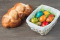 Easter wicker basket with colored eggs and Easter bread on grey wooden board. Royalty Free Stock Photo