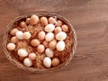 An Easter wicker basket with white and beige eggs stands on a wooden brown background. Royalty Free Stock Photo