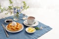 Easter yeast bread plaited to a nest with an egg, coffee, butter and jam on a blue napkin and a white table, many have to spend