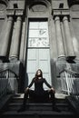 Eastern beautiful woman wearing biker jacket poses in backyard of vintage apartment house