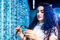 eastern ethnic woman in white medical coat robe selling glasses in optical store