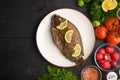 Eastern or European cuisine, Fried fish with fresh vegetables, on a wooden black background. I also eat healthy food. Seafood, Royalty Free Stock Photo