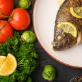 Eastern or European cuisine, Fried fish with fresh vegetables, on a wooden black background. I also eat healthy food. Seafood, Royalty Free Stock Photo