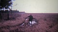 EASTON, MARYLAND 1972: Old man walking through mud puddle in open grass field.