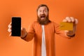 gingerhead bearded man showing blank smartphone and credit card, studio Royalty Free Stock Photo