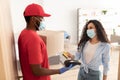 Black deliveryman holding POS terminal lady paying with bankcard